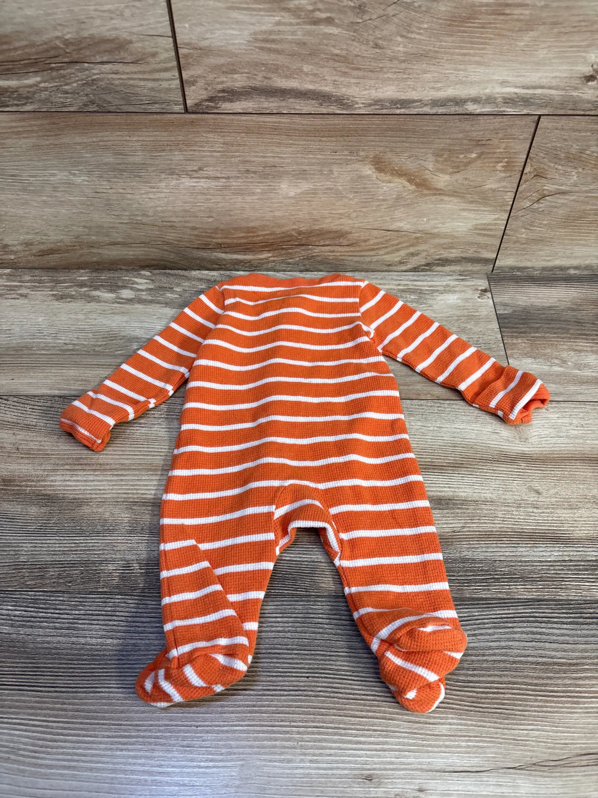 Just One You orange and white striped waffle knit newborn sleeper on a wooden background