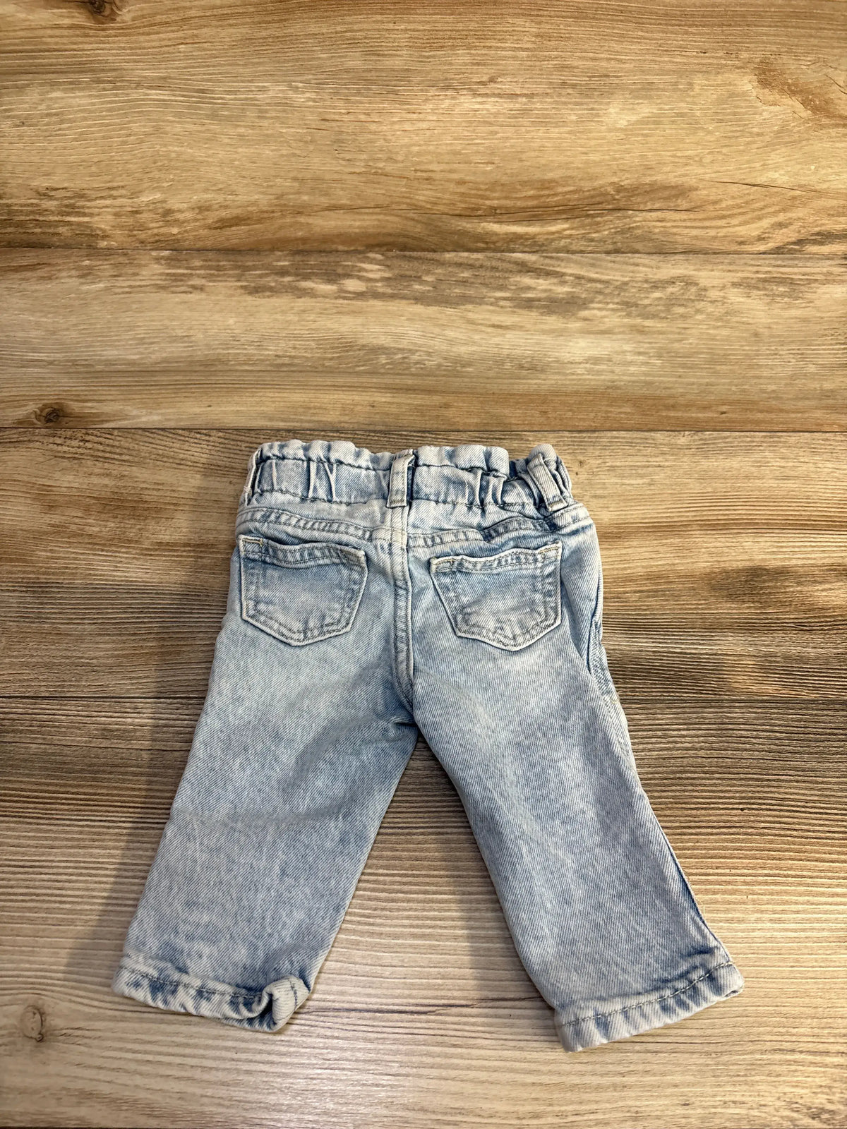 Rear view of Gap Denim Just Like Mom Jeans showcasing elastic waistband and back pockets on a wood surface