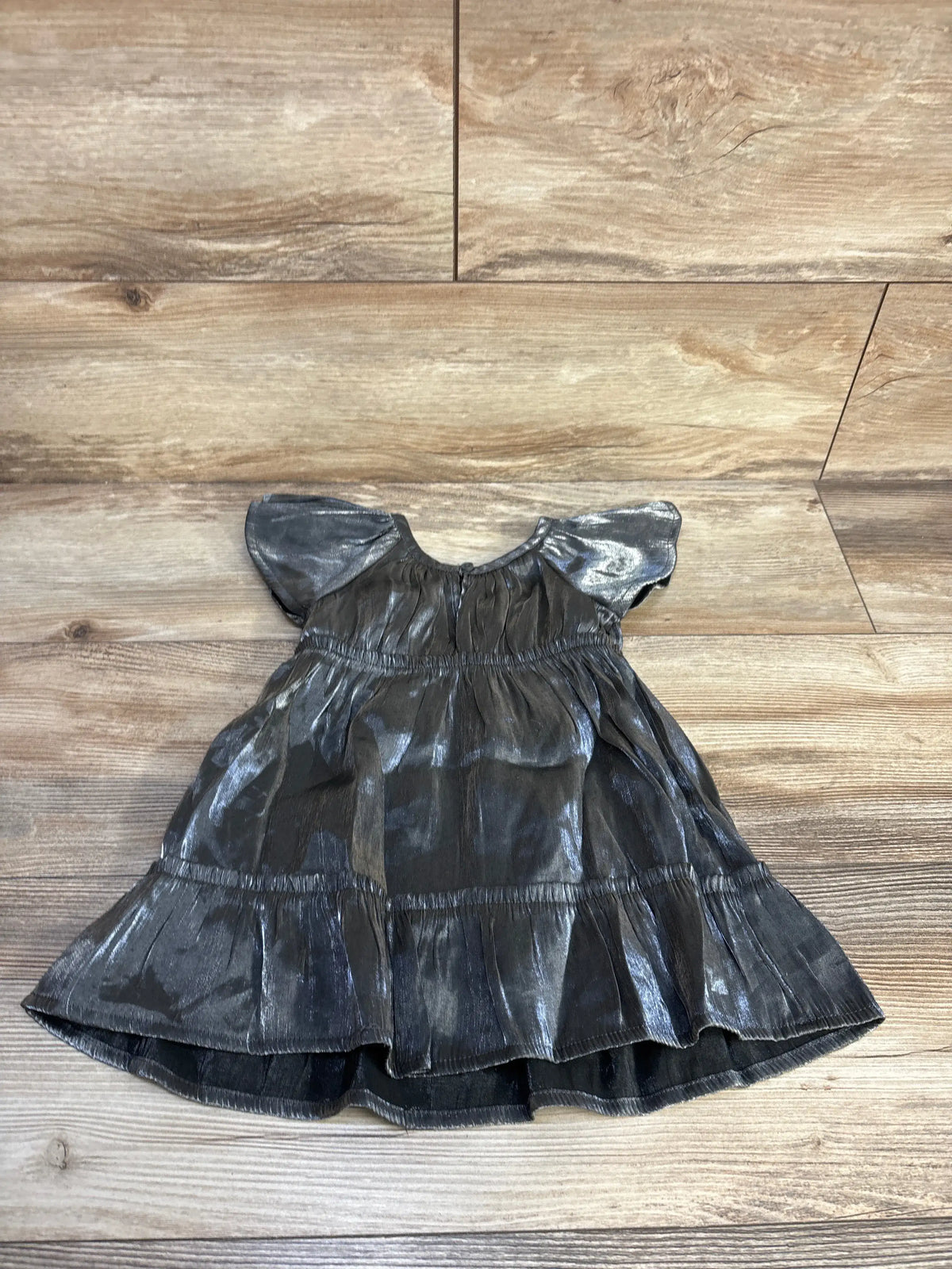 Front view of Wonder Nation silver metallic flutter sleeve dress showcasing tiered skirt on a wood plank background