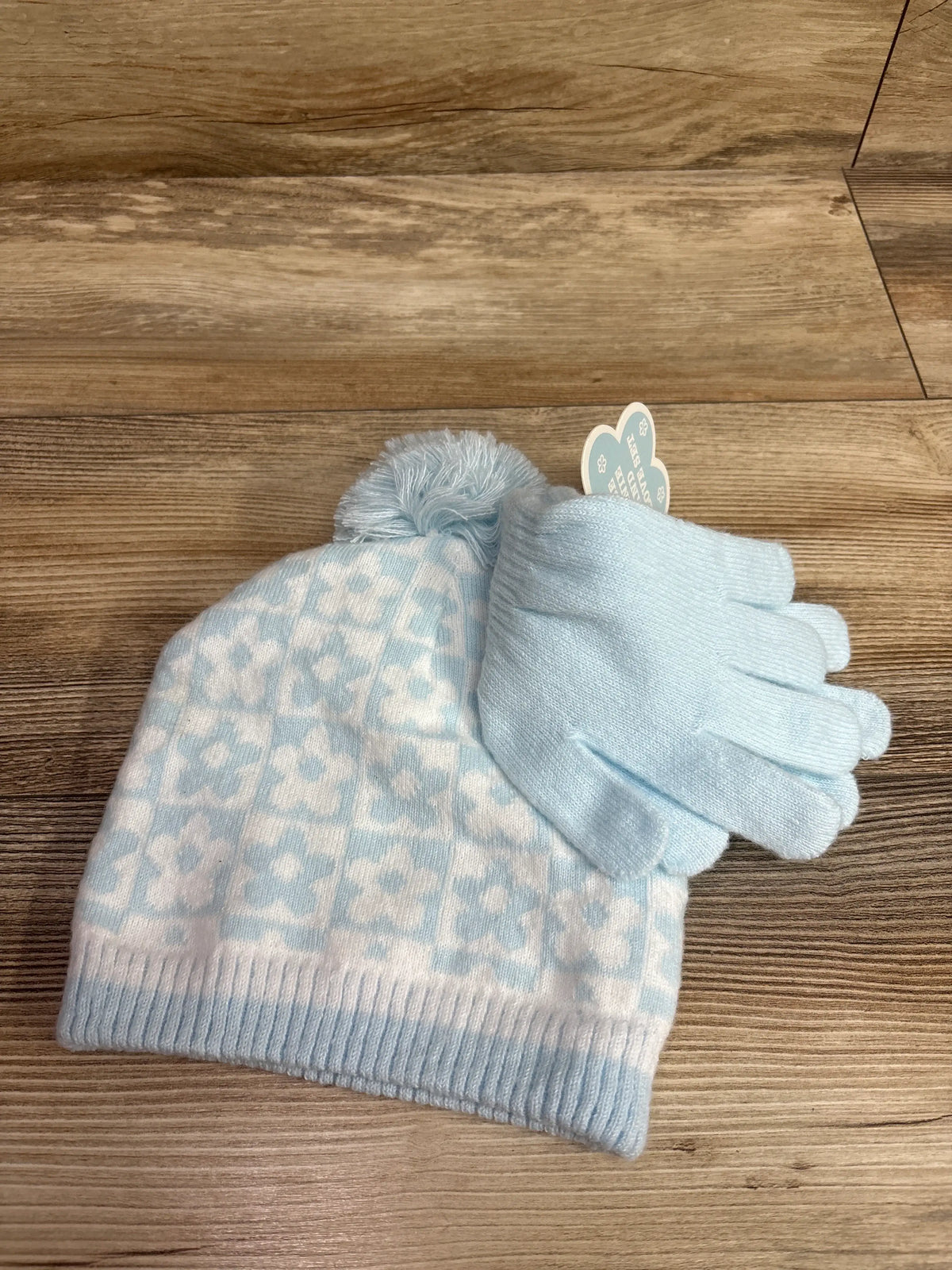 Light blue Me n Mommy To Be pom-pom beanie and matching gloves set on a wooden surface