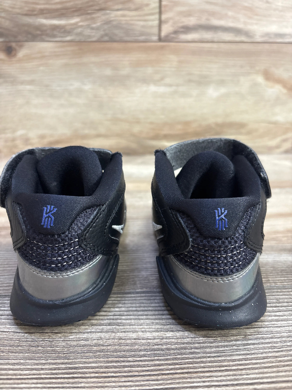 Back view of black Kyrie Irving toddler sneakers with mesh detail on wood floor