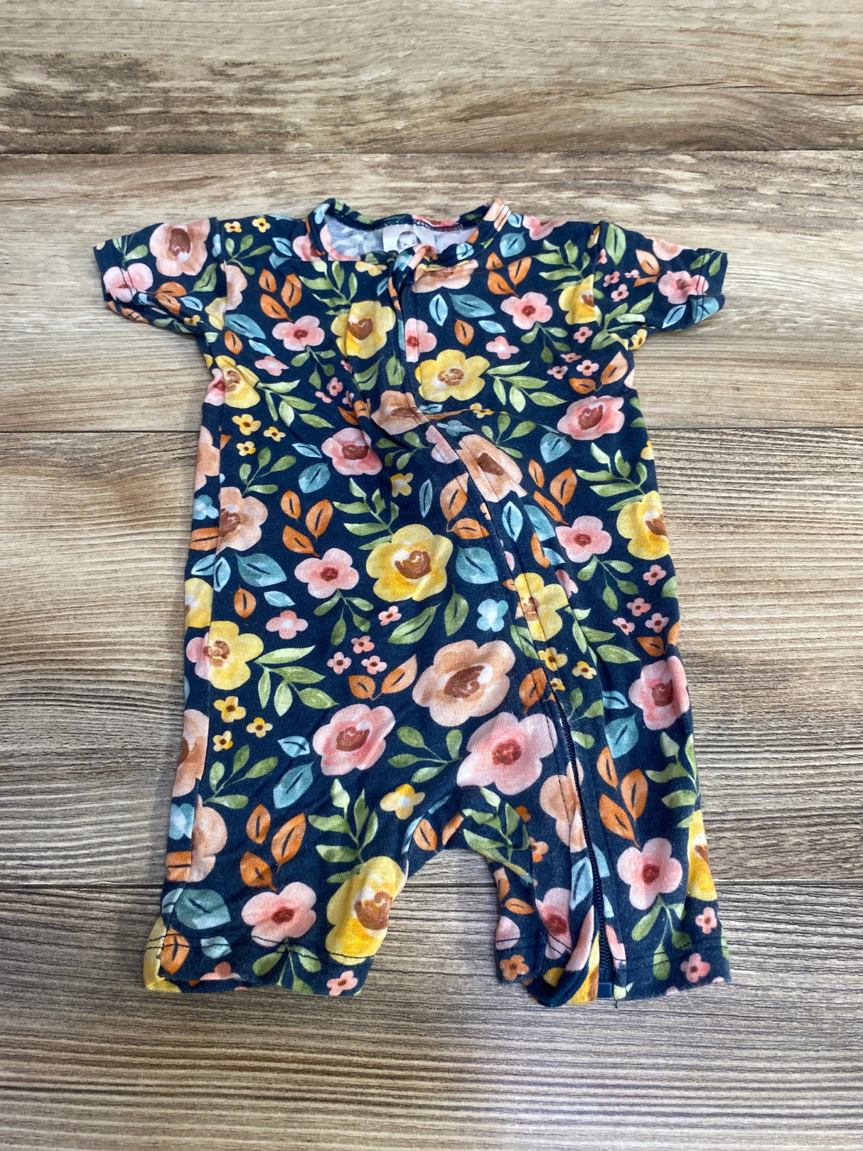 Top down view of newborn Gerber floral zip romper with navy background, front zipper, laid flat on wood