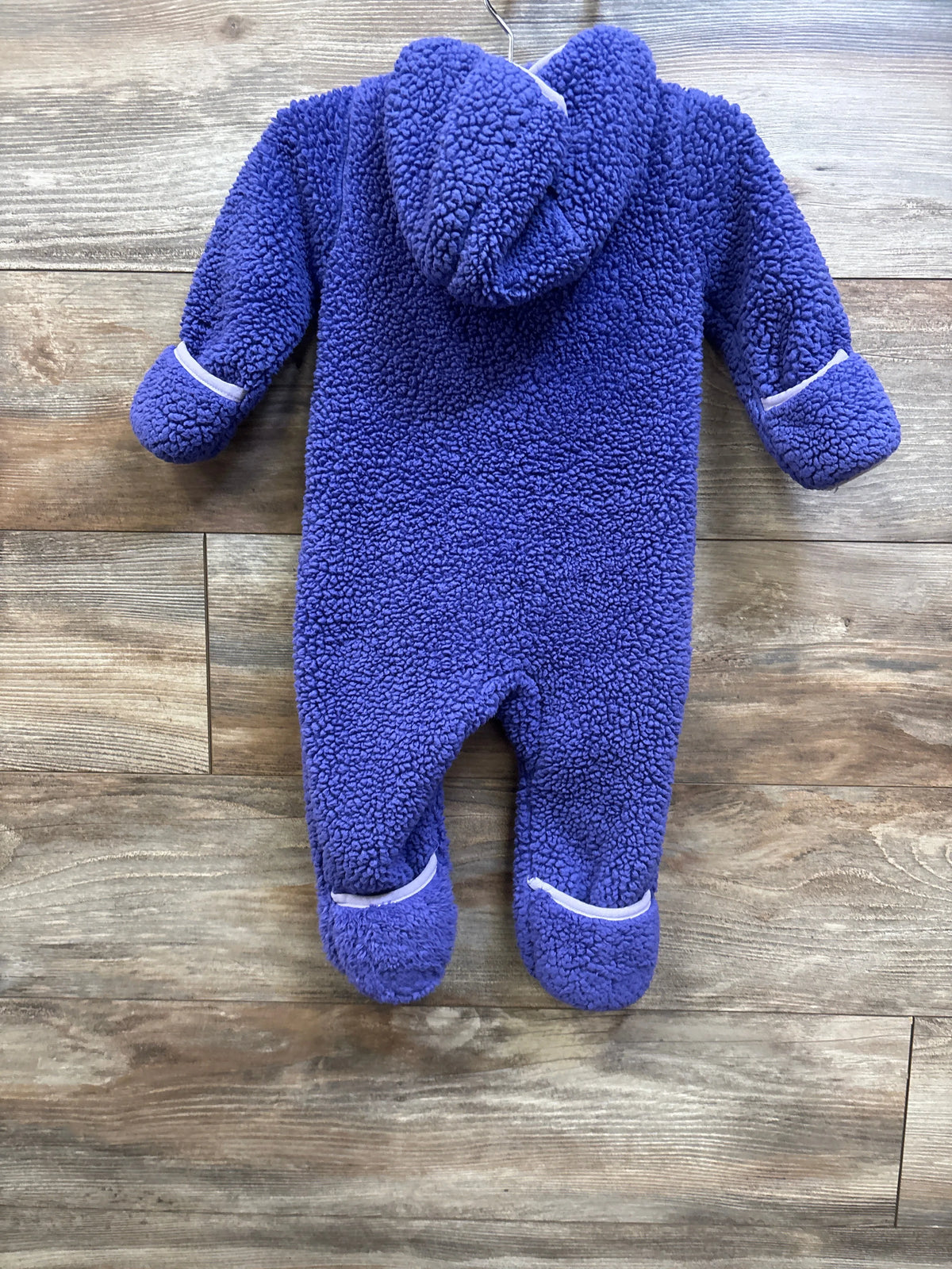 Purple Snozu Sherpa hooded bunting baby suit on a wood-grain background