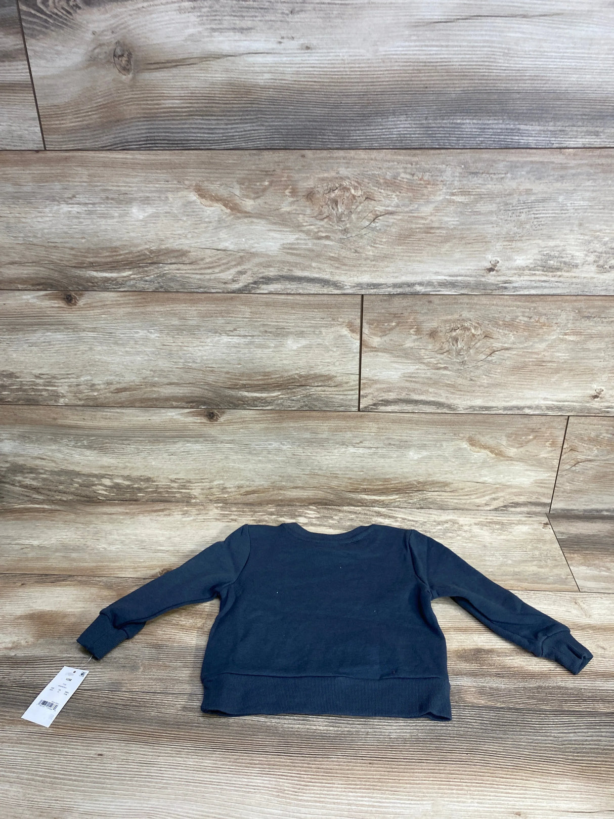 Navy blue long sleeve toddler sweatshirt laid flat on wooden floor, resale kids clothing
