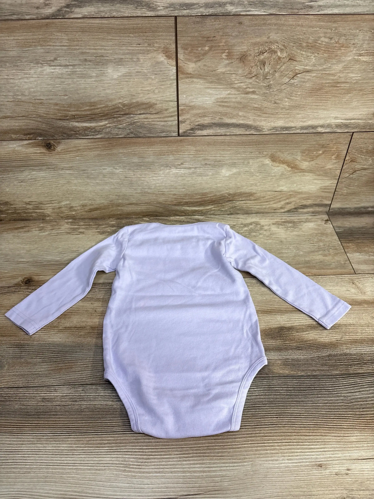 Top view of purple long-sleeve bodysuit for ages 18 to 24 months laid flat on a wood floor
