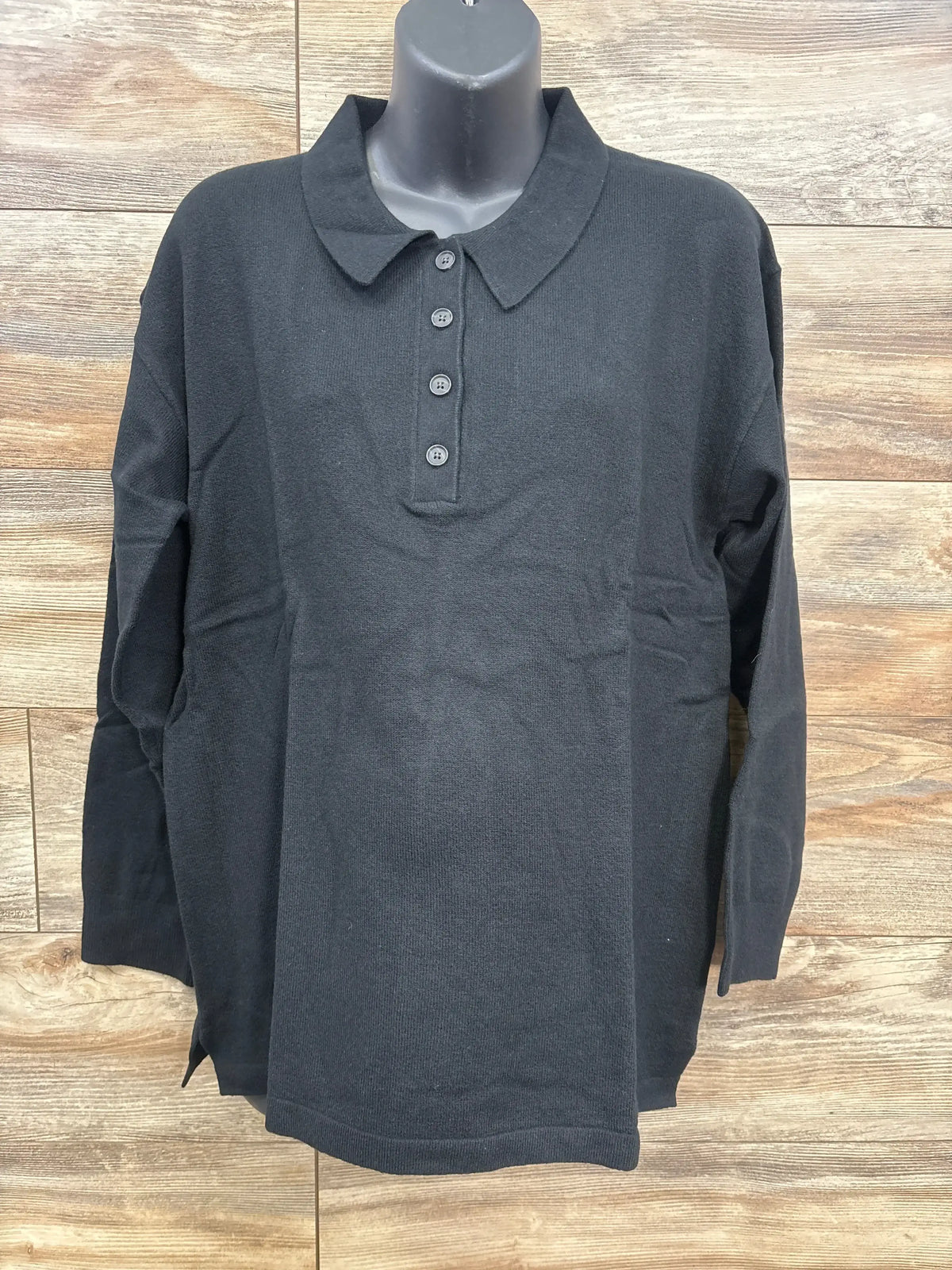 Front view of black Gap CashSoft maternity polo sweater (large) showing collar, 4-button placket and long sleeves on wood backdrop