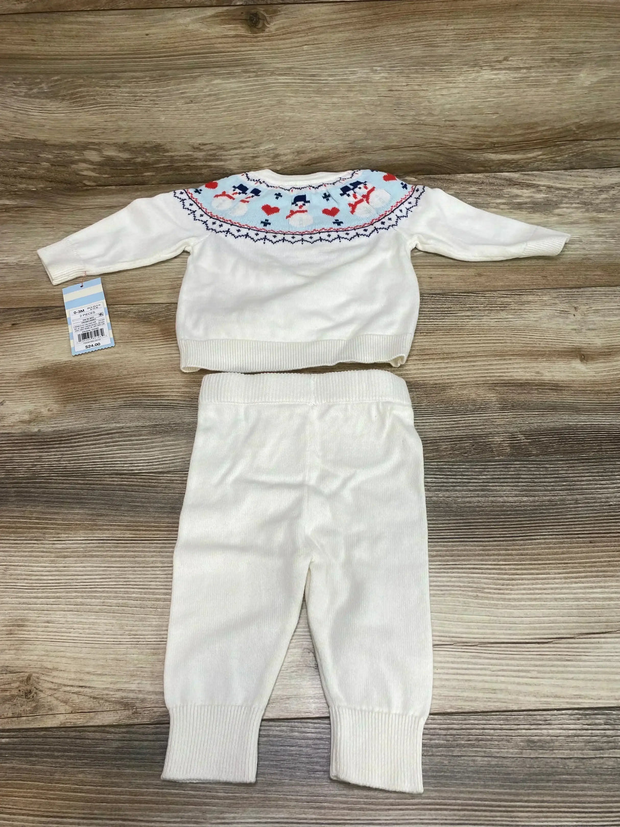 Flat lay of white Cat & Jack baby sweater and pants (0-3m) showing Fair Isle snowman yoke and ribbed cuffs on wood