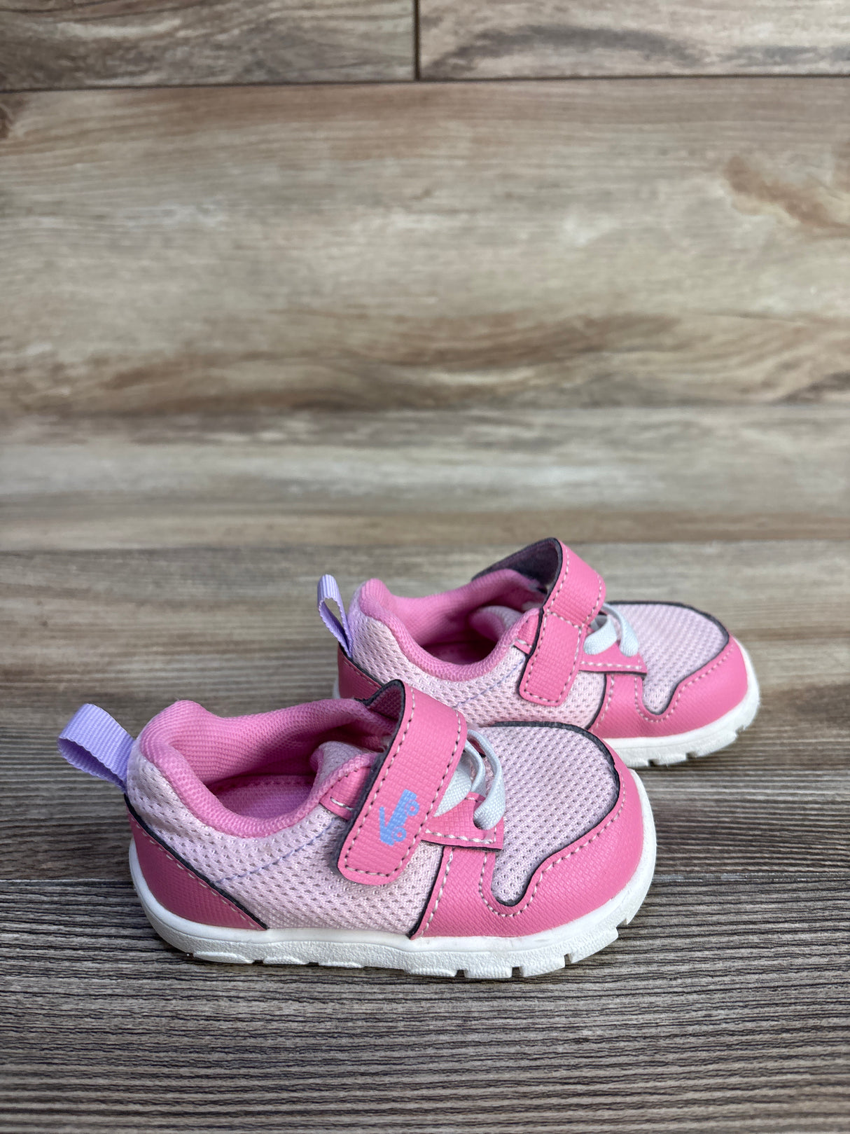 Side view of pink See Kai Run sneakers size 4C with mesh upper, hook-and-loop strap and white sole on wood surface