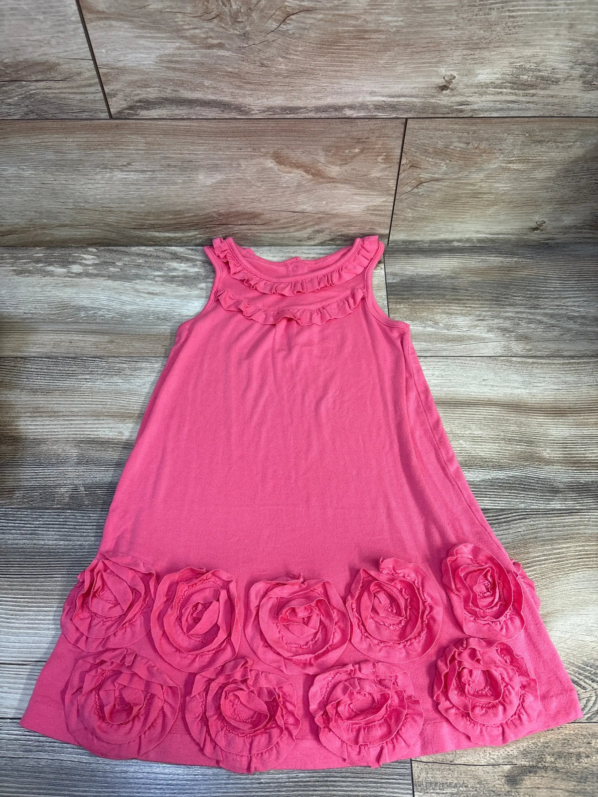 Flat lay of hot pink Janie and Jack rosette knit dress size 4T showcasing layered rosette trim along hem and ruffled neckline on wood floor