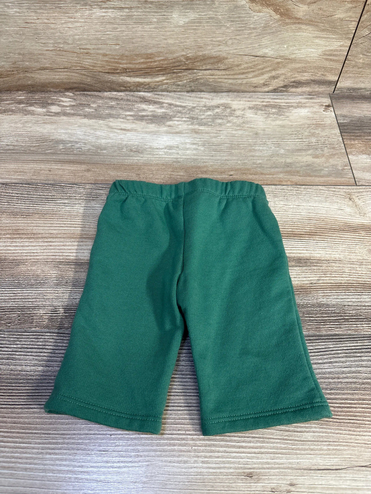 Front view of green Cat & Jack pull-on joggers in Newborn size showcasing elastic waistband and relaxed fit on a wood-look floor