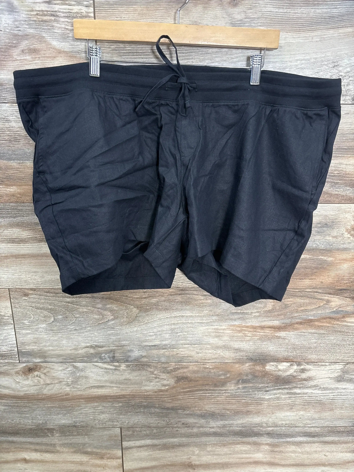 Front view of Gap maternity shorts showcasing black linen-cotton fabric, under-belly drawstring waist, and slant pockets on a wooden hanger