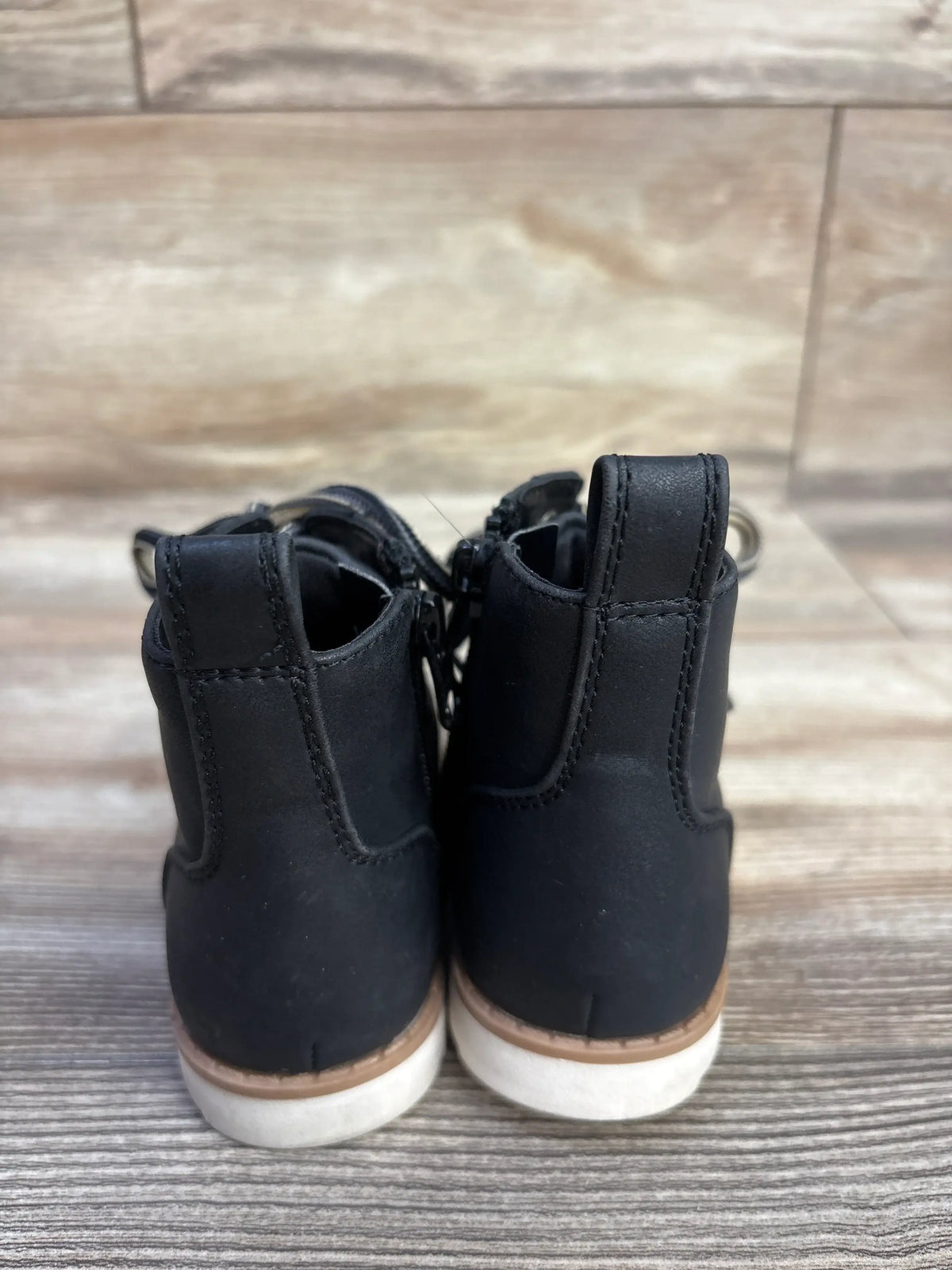 Rear view of Cat & Jack Greyson boots, black size 6C, showing pull tabs and white soles on a wood-look floor