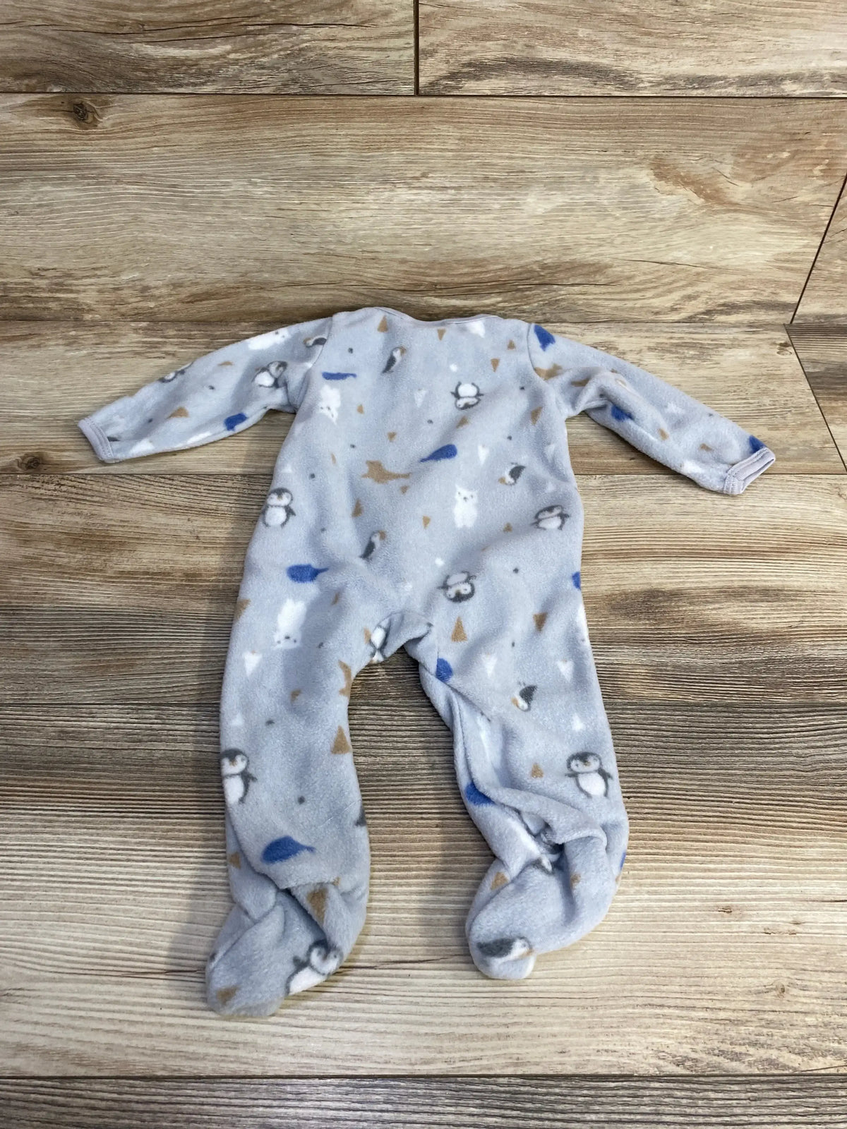 Flat lay of grey Sterling baby animal-print footed sleeper showing penguin and bear pattern, long sleeves and enclosed feet on wood background