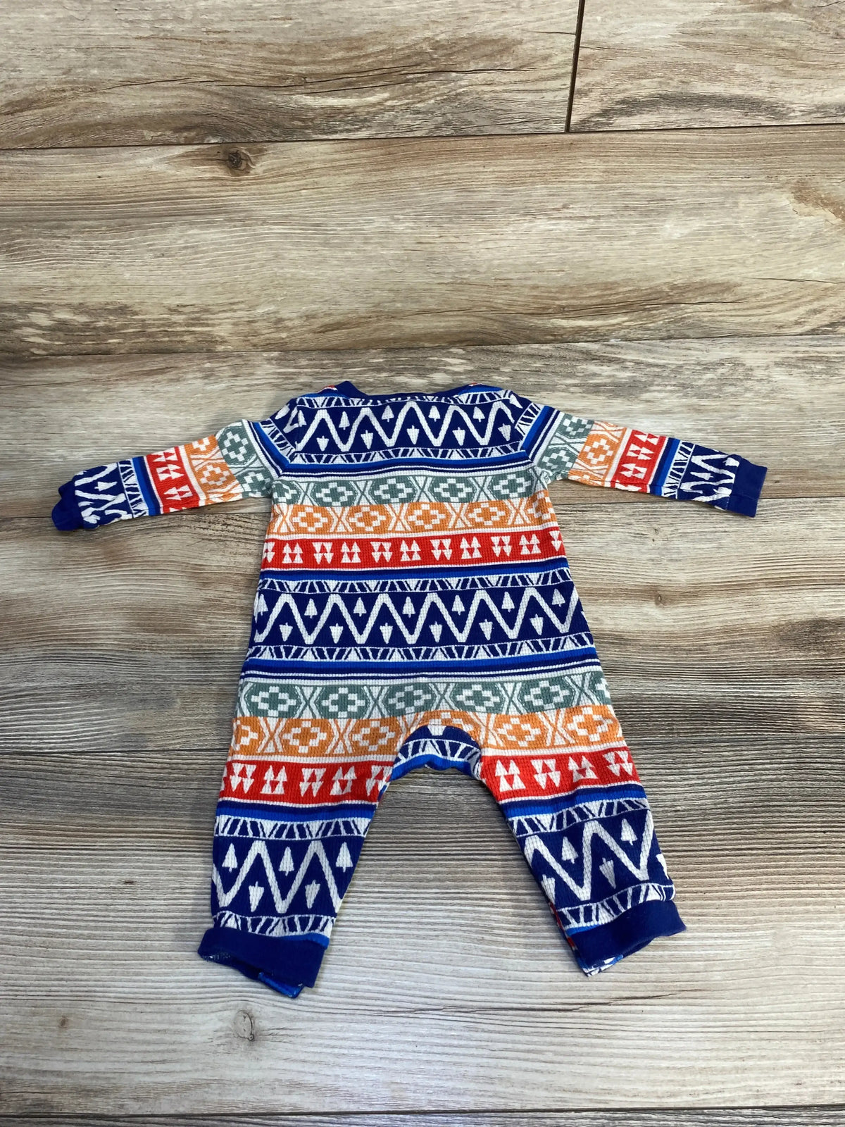 Colorful geometric patterned baby onesie on wooden floor