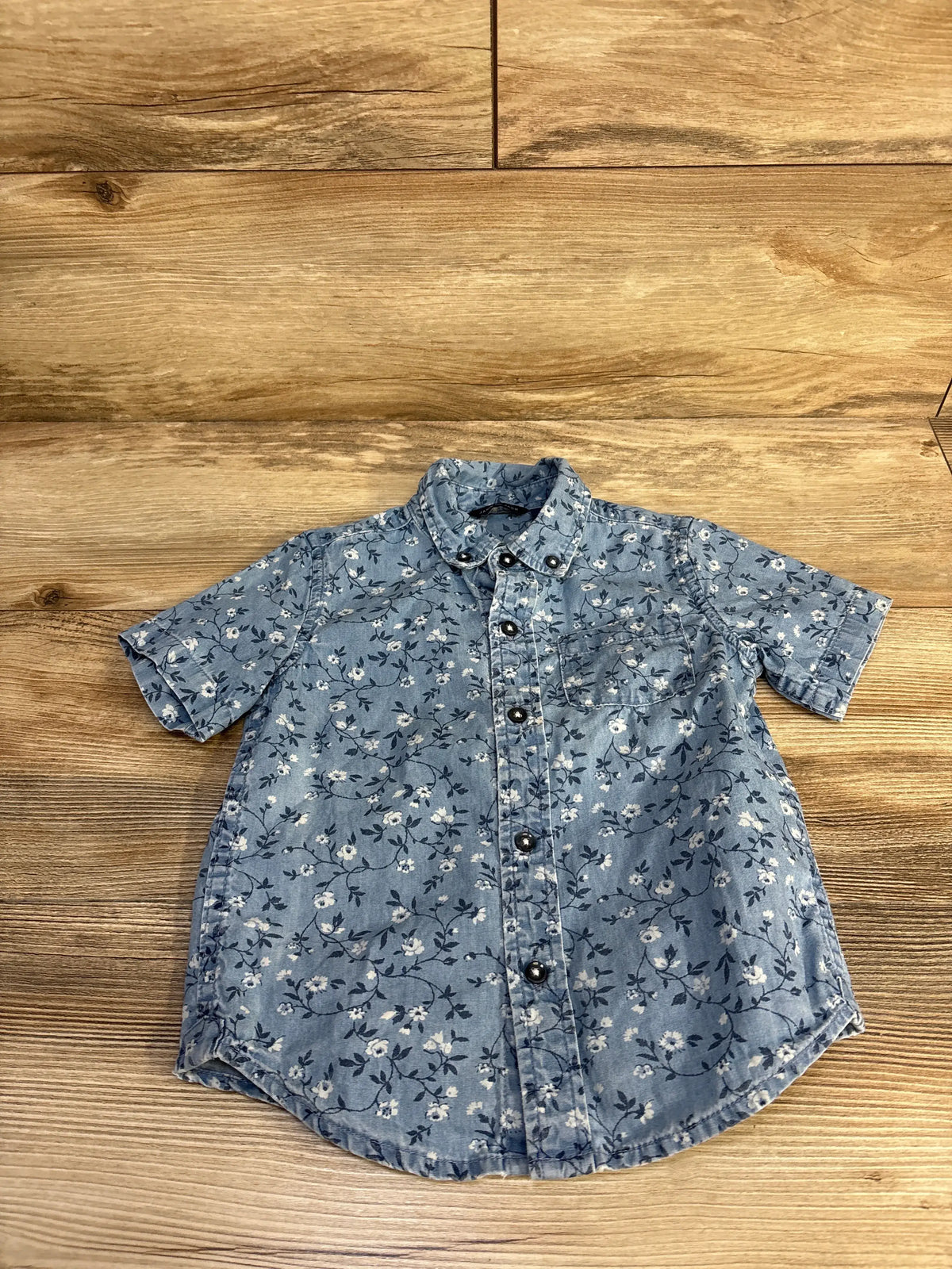 Front view of Janie and Jack blue floral chambray shirt in size 2T with chest pocket and shirttail hem