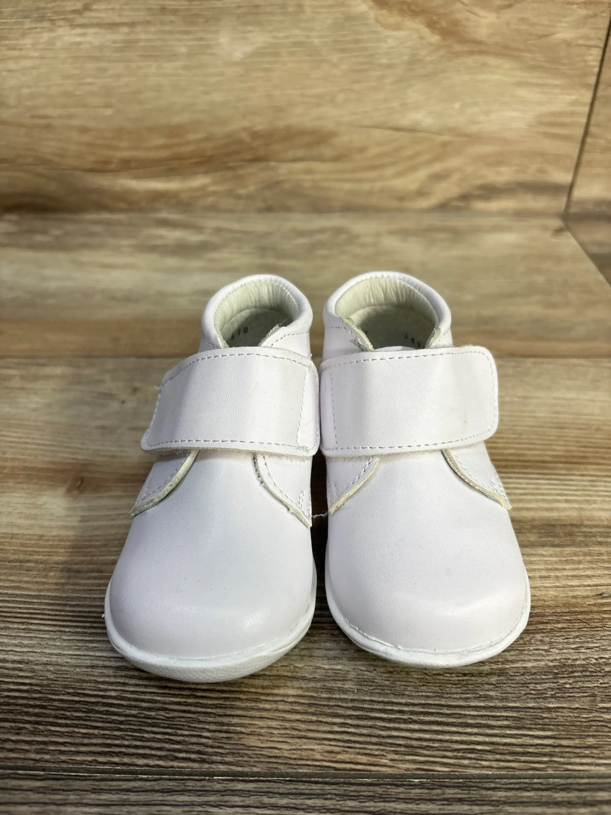 A pair of white Alegria Kids patent leather first walker shoes with hook-and-loop straps.