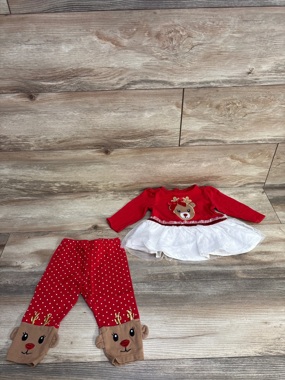 Red and white reindeer baby outfit set with tutu top and polka dot leggings on wood floor