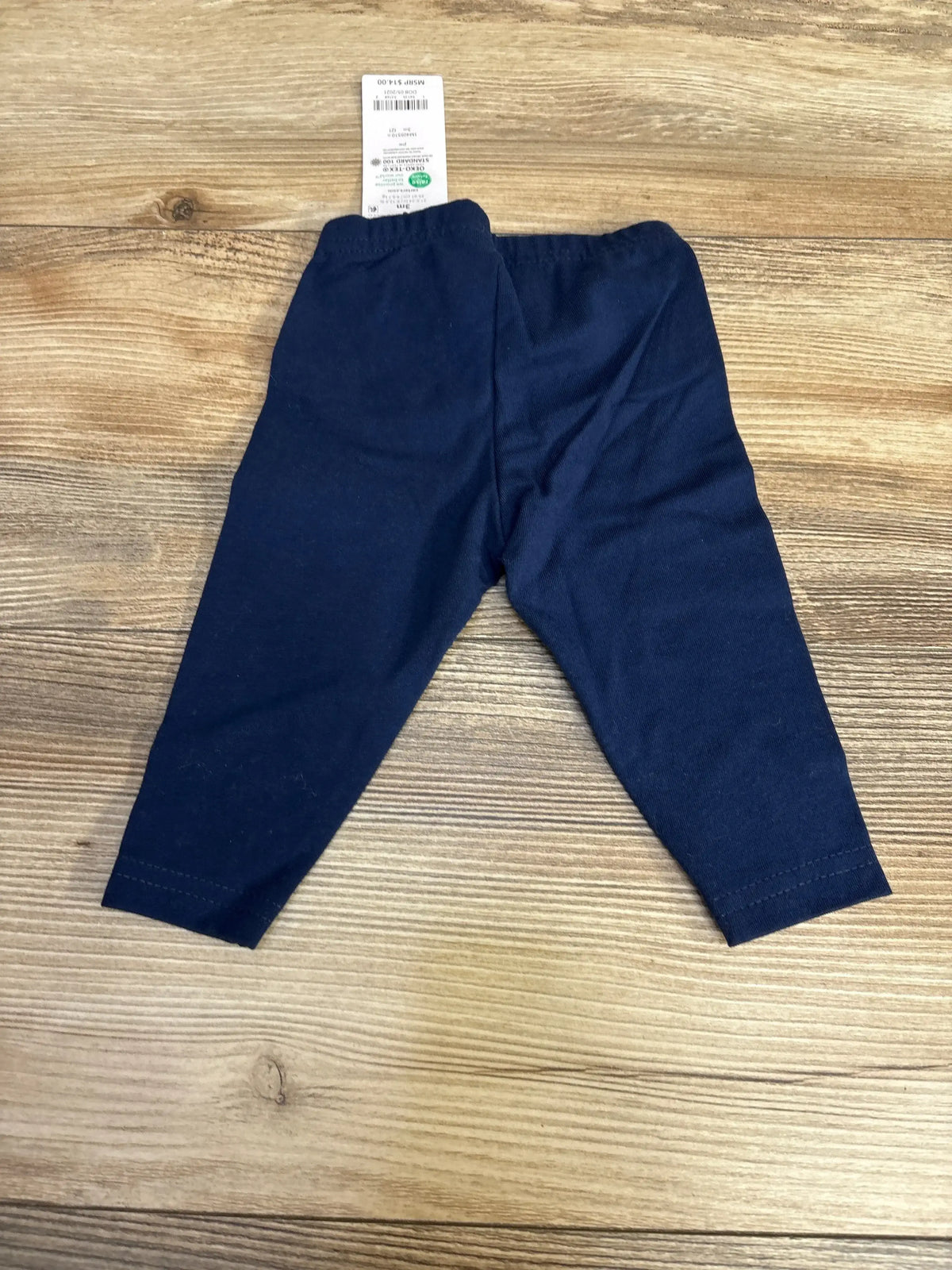 Navy blue baby leggings with price tag on wood background