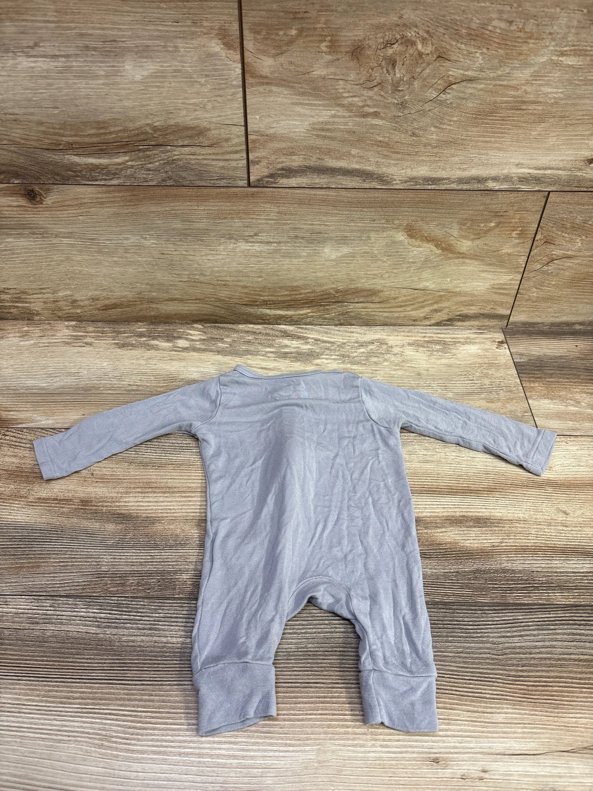 Top view of a grey Cloud Island modal sleeper with long sleeves and cuffed ankles on a wood-look floor