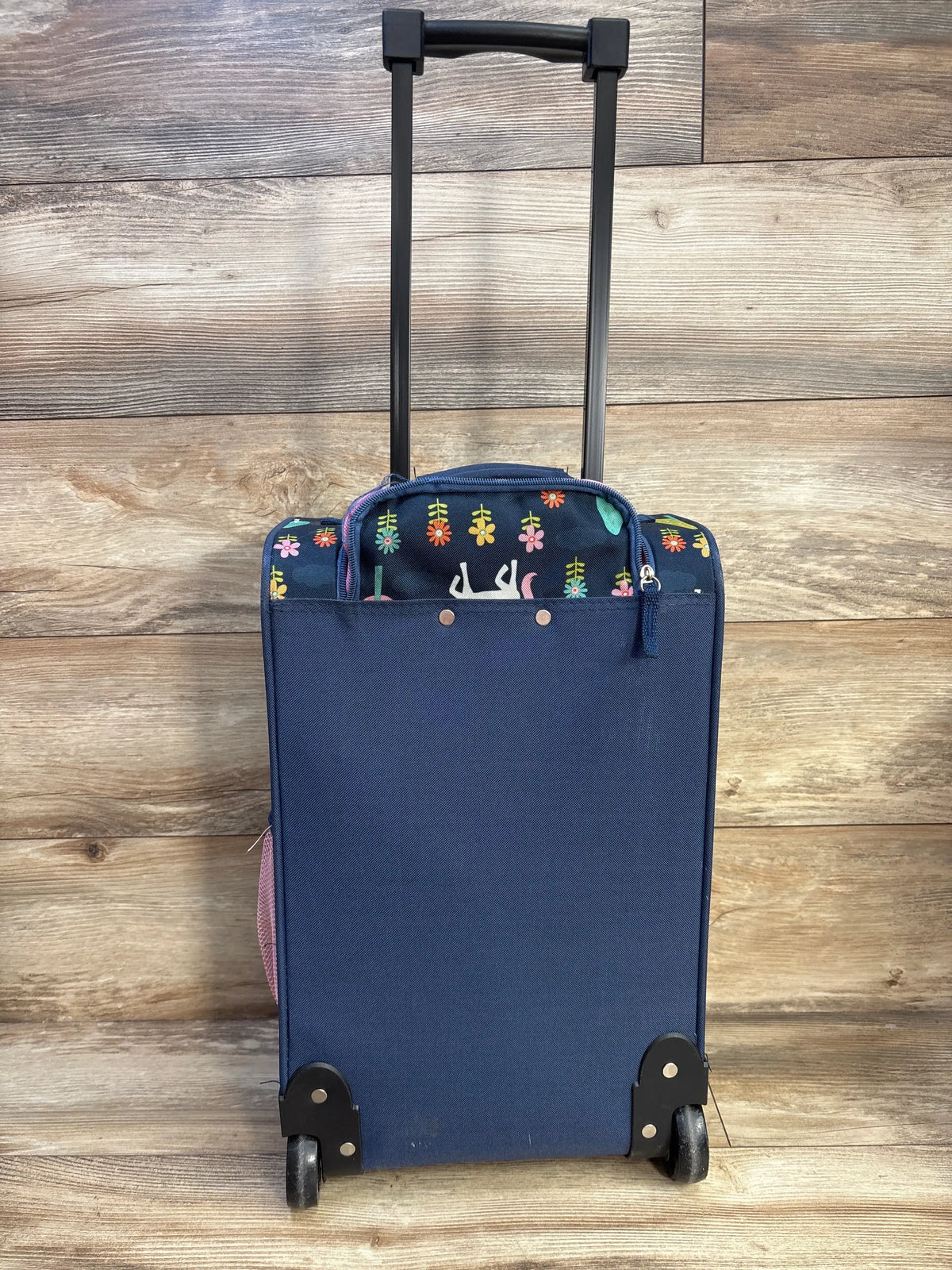 Back view of Crckt Kids’ Softside Carry On Suitcase showcasing telescopic handle, wheels, and side bottle holder on wood flooring