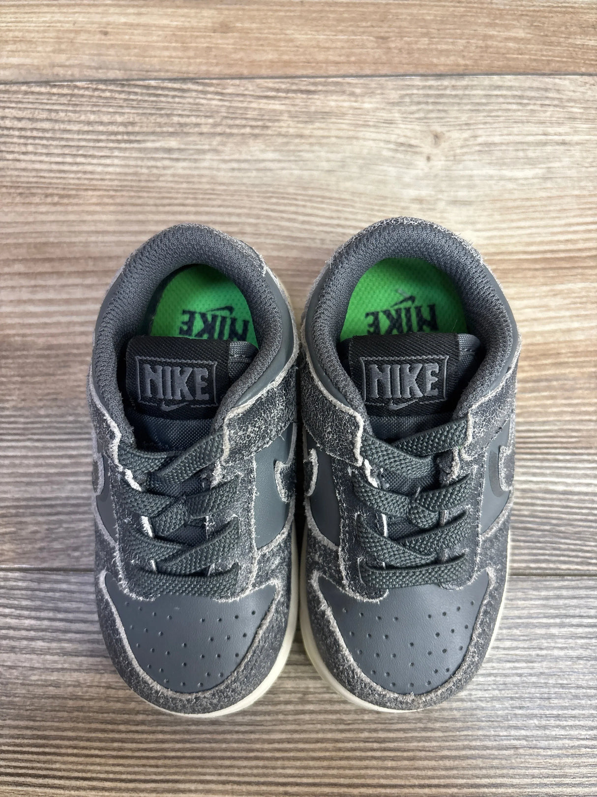 Gray Nike toddler sneakers with green insole, kids' athletic shoes on wood floor