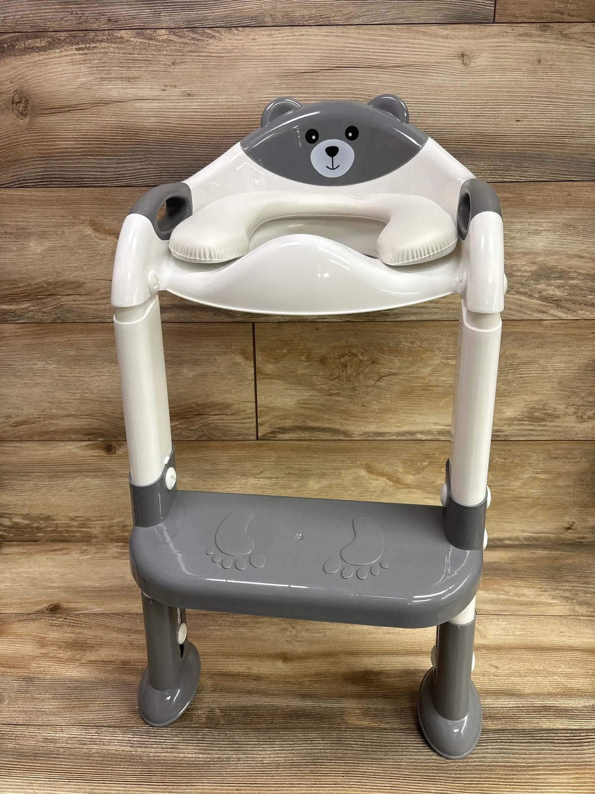 Front view of grey SKYROKU potty training seat showcasing bear design, padded seat, handles, and footrest against a wood background