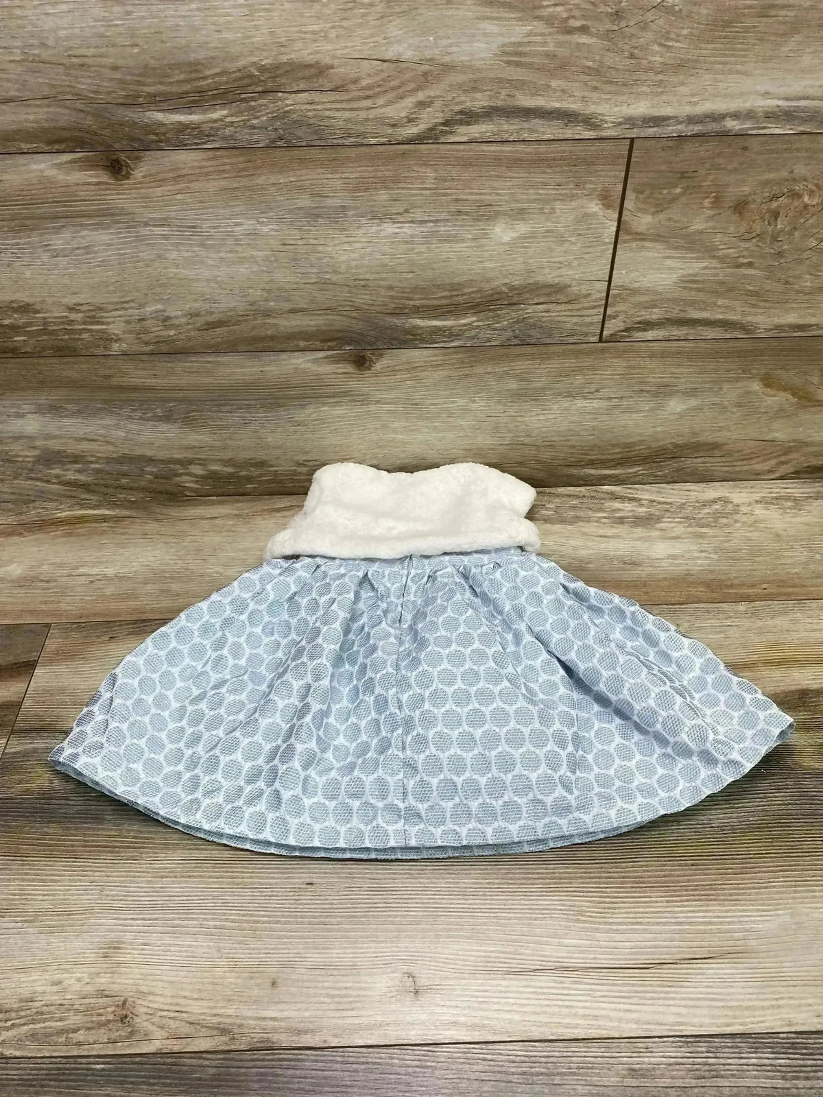 Flat lay front of Popatu 2-piece blue polka dot dress with white faux fur vest showcasing textured skirt on wood floor background