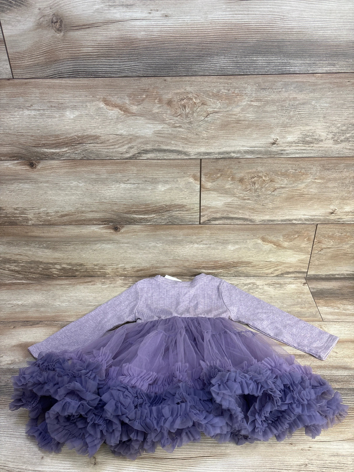 Flat lay of purple ribbed long-sleeve toddler dress (5T) showcasing layered tulle skirt with ruffled hem on light wood background