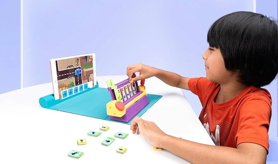 Child playing educational coding game with tablet and colorful instruction tiles on white table