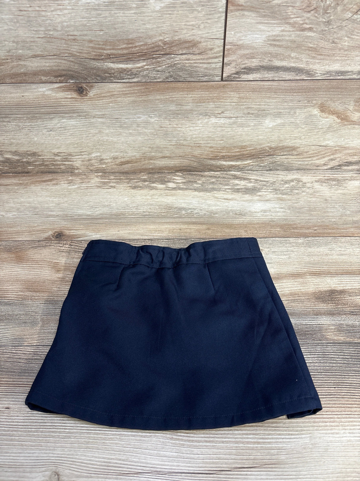 Navy blue toddler or child’s skirt laid flat on wooden floor, suitable for kids clothing resale