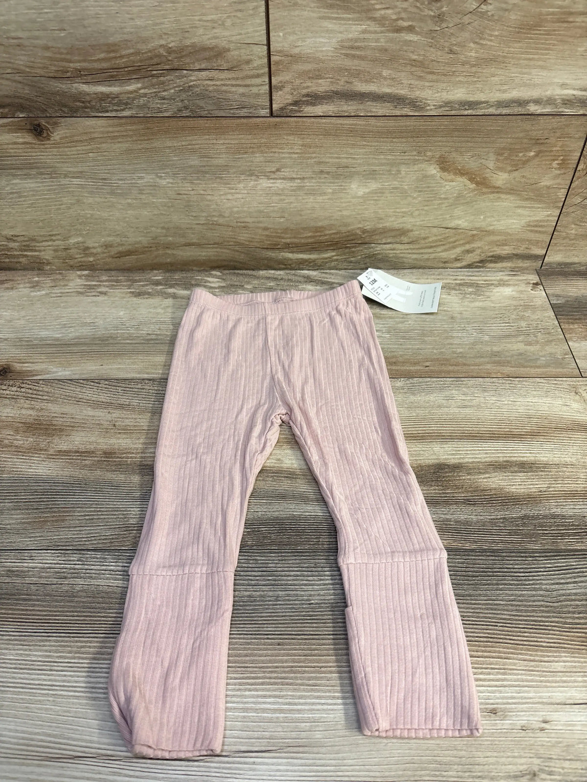 Flat lay of Cloud Island convertible foot leggings, light pink, showing ribbed fabric and fold over feet on wood background