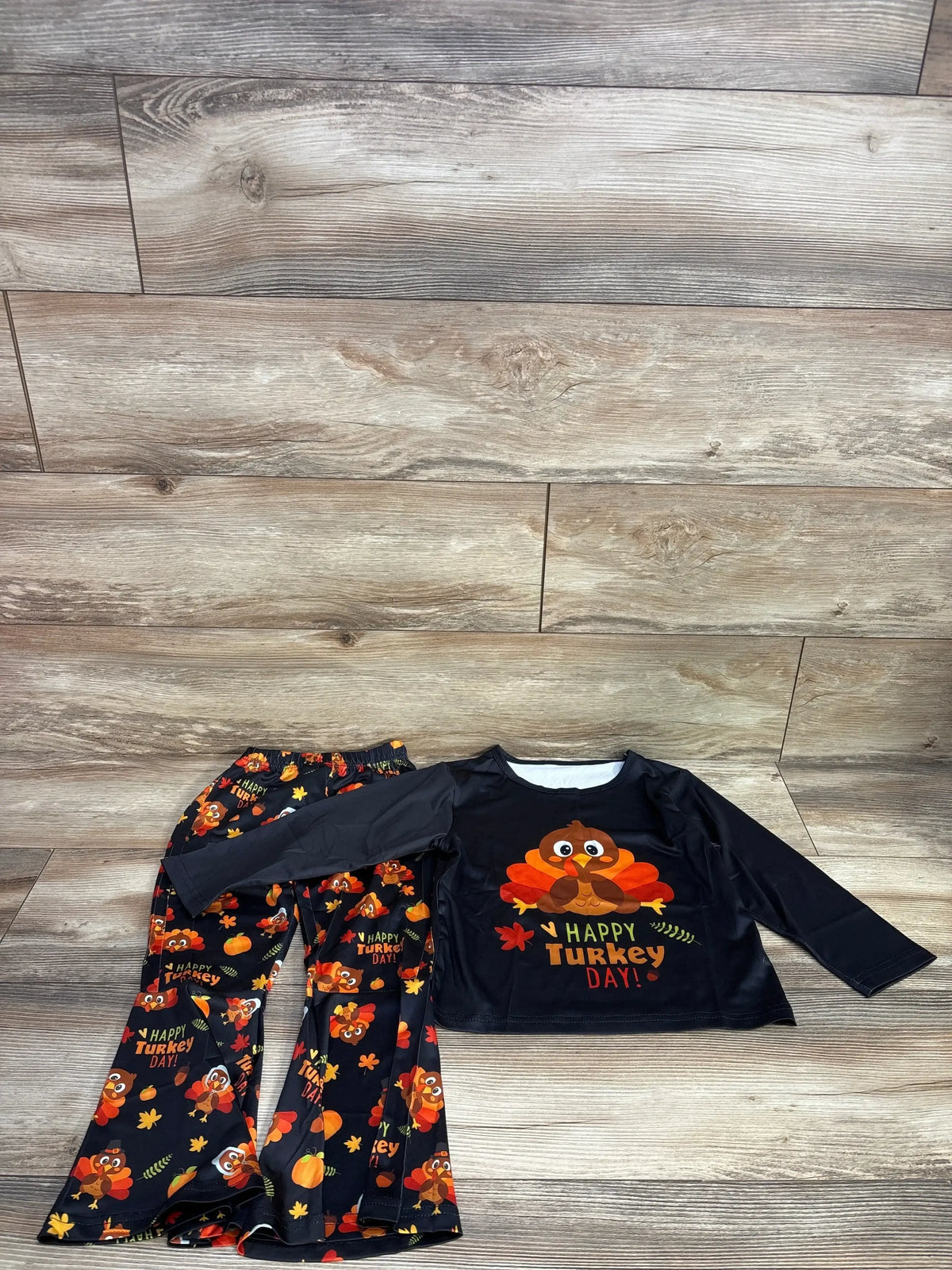 Kids Thanksgiving outfit with Happy Turkey Day shirt and turkey print pants on wood floor