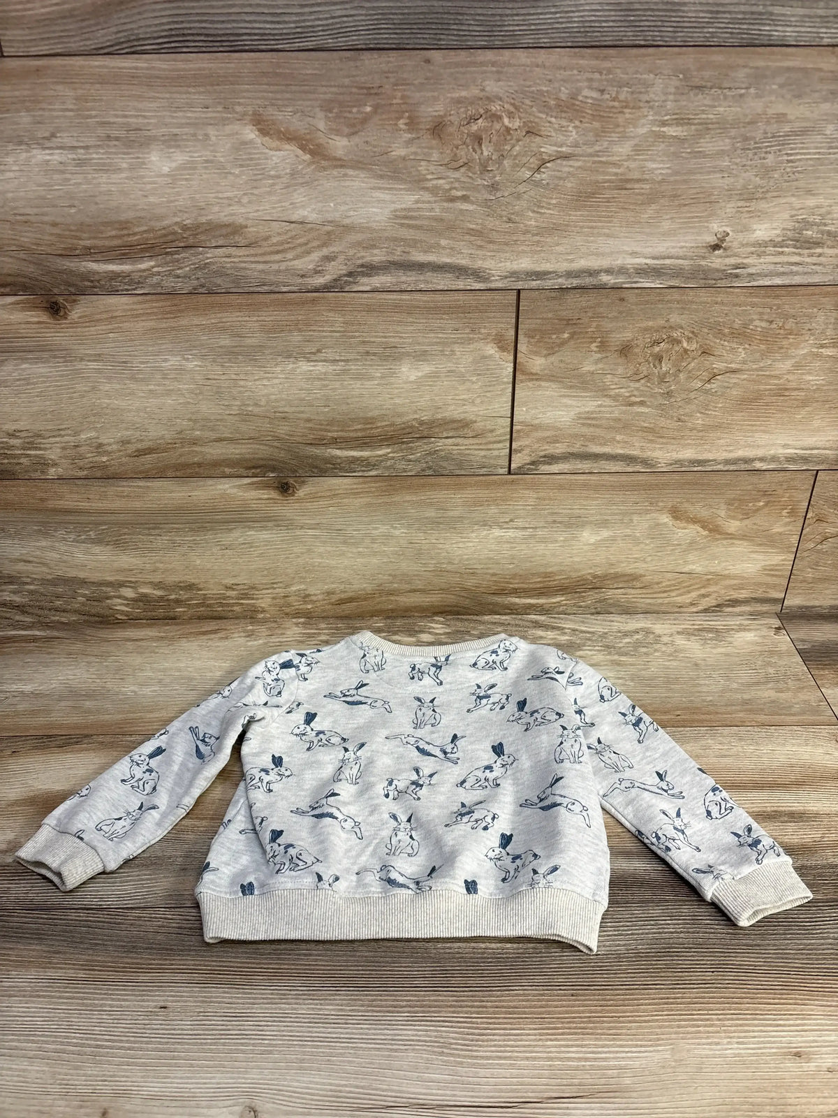 Gray children's bunny print sweatshirt on wooden floor background