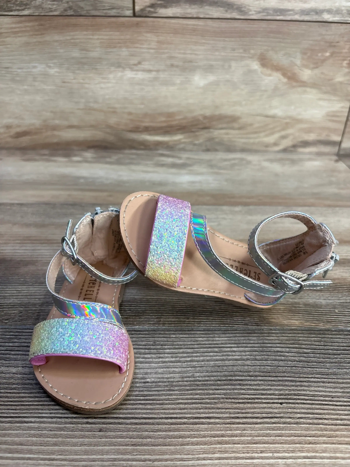 Angled top view of Seychelles toddler sandals (size 5C) showing pink iridescent glitter toe strap and silver ankle strap on wood floor