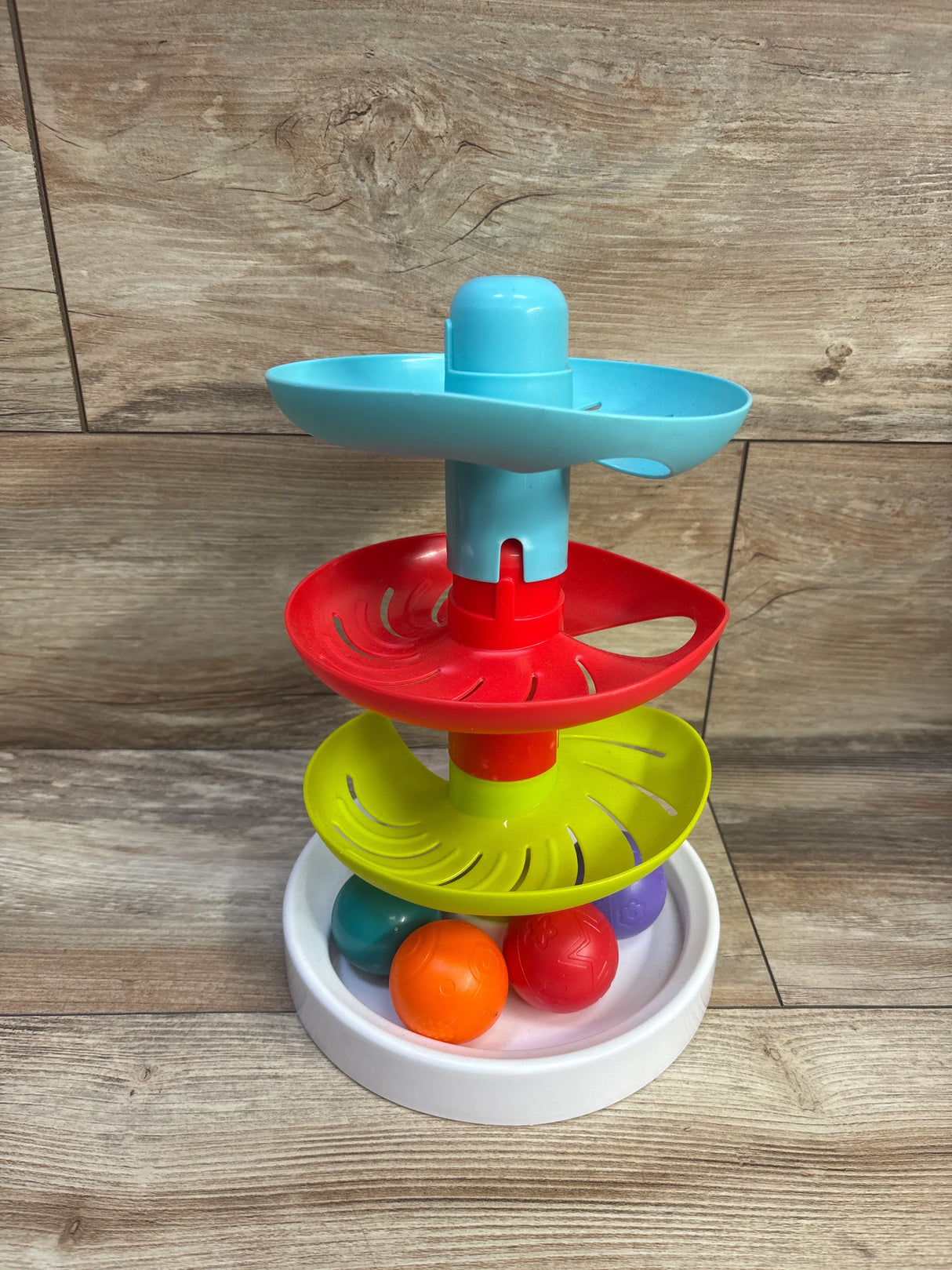 Front view of Lollipop Spinning Ball Drop Tower showcasing three spiral tiers and four colorful balls with wood background