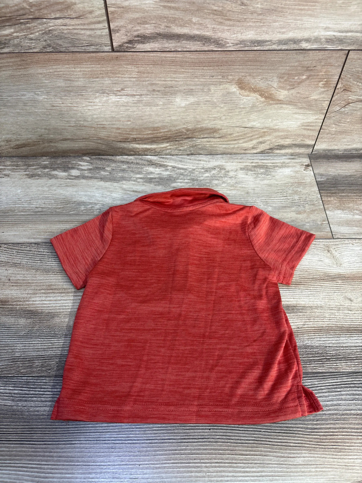 Rear view of Okie Dokie active polo shirt in red with short sleeves and collar on a wood-look floor