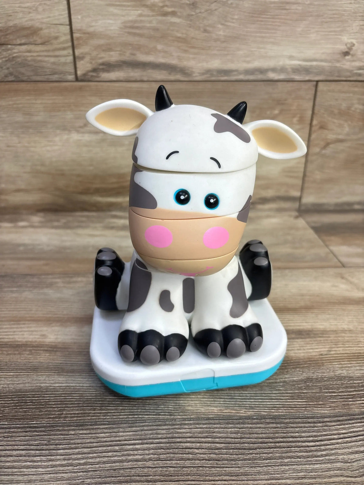 Front view of Stack-a-Roos baby cow stacking toy showing stacked cow-shaped rings and molded feet on a light wood background