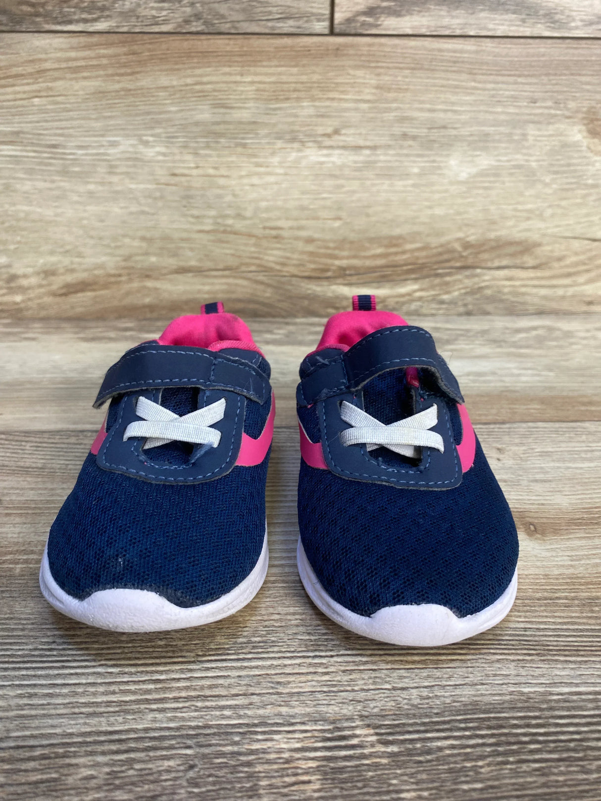 Navy blue and pink toddler sneakers with velcro straps on wood background