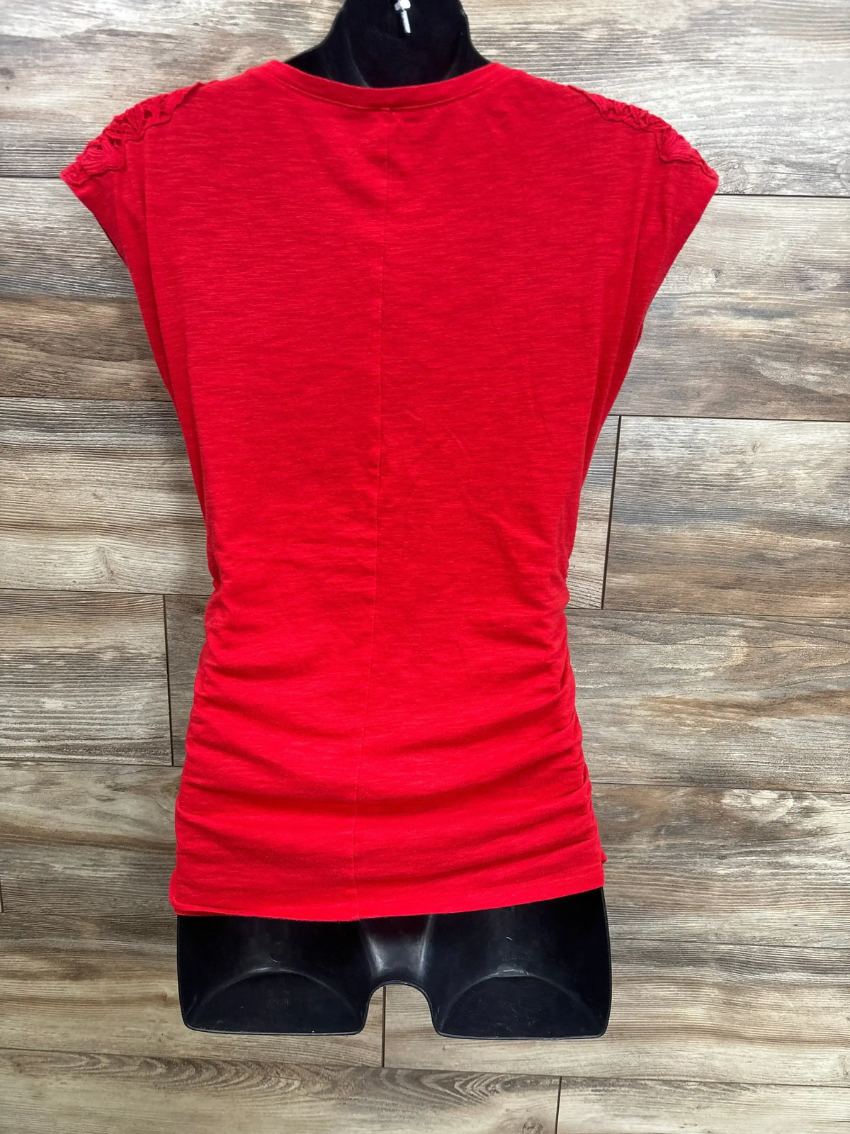Red short sleeve maternity top with ruched sides, displayed on mannequin, wood background