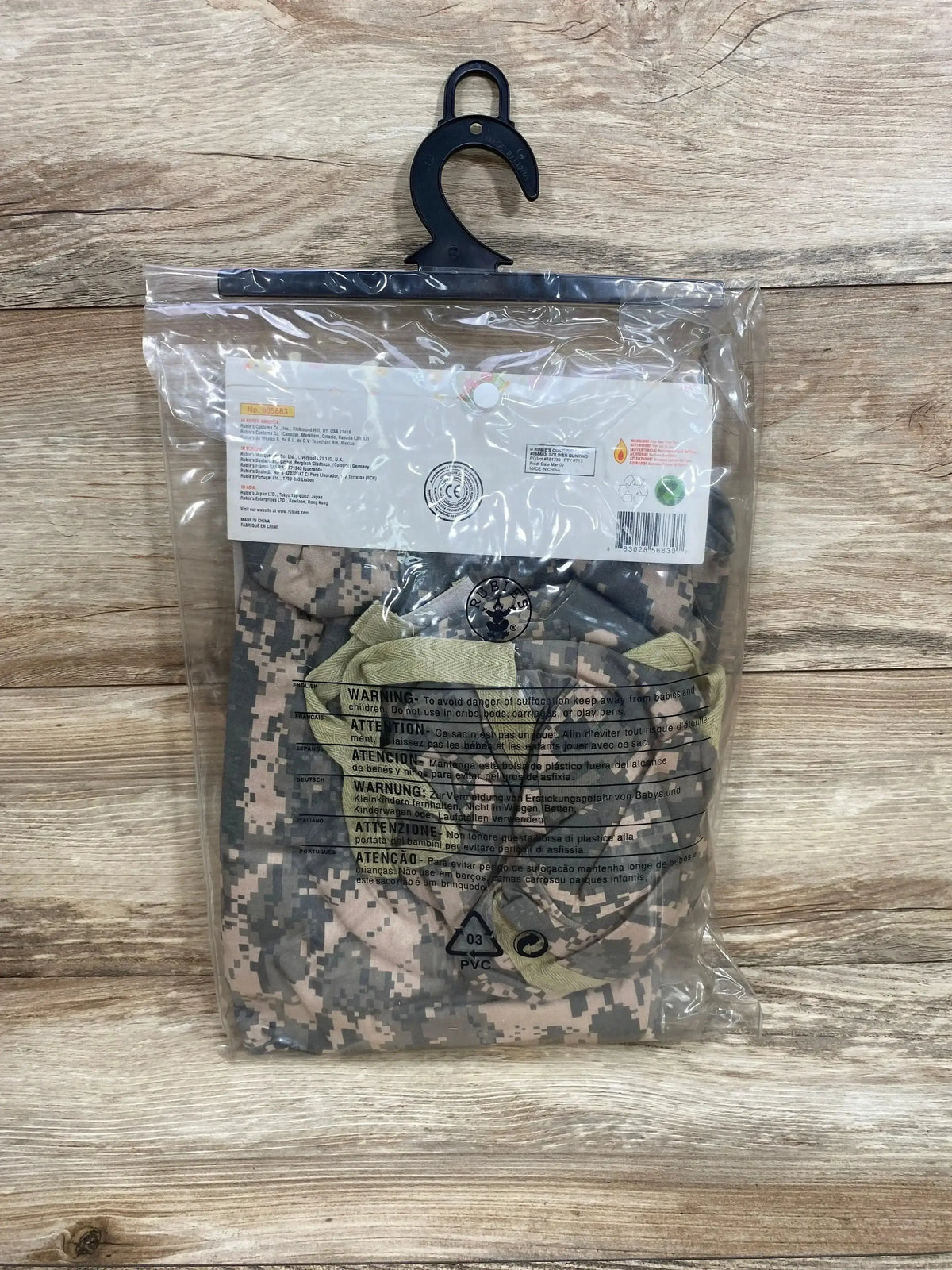 Front of Rubie’s soldier bunting size 0-9 months showing camouflage fabric and hood in clear packaging on wood background