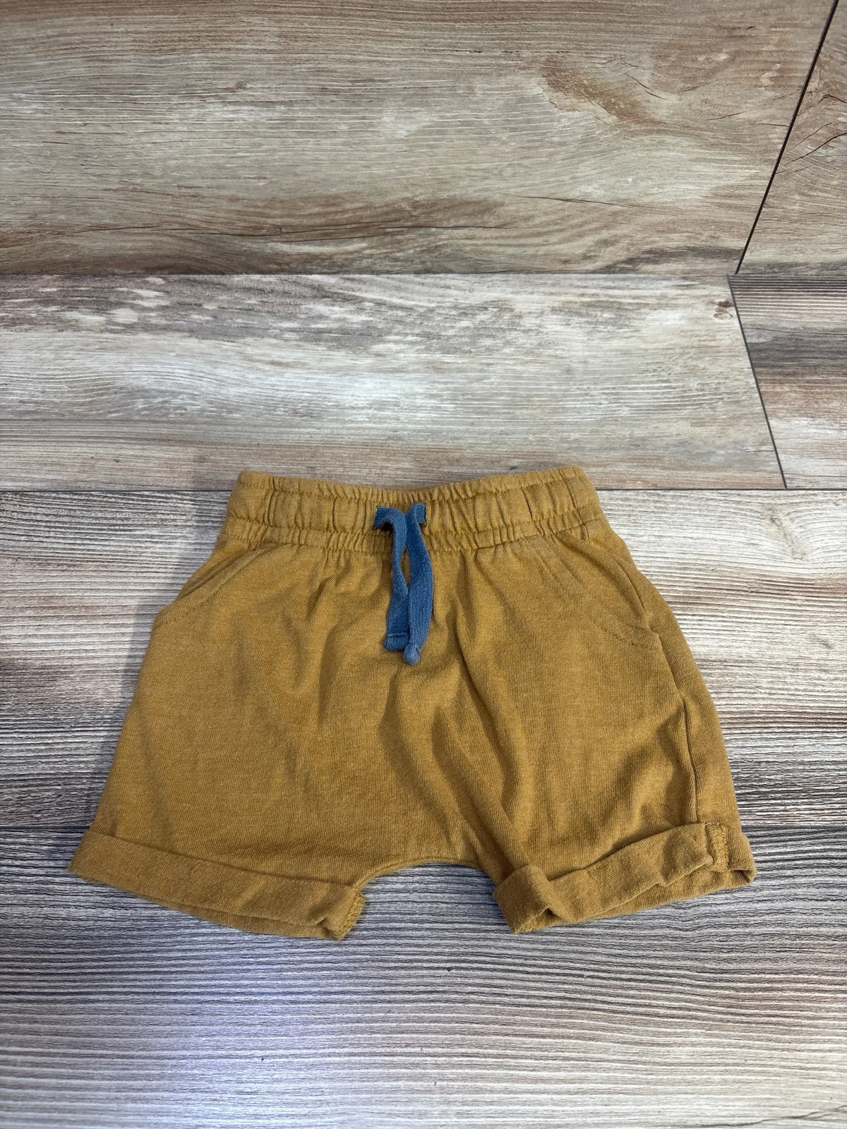 Brown Cat & Jack drawstring shorts for baby size 12m on a wooden surface