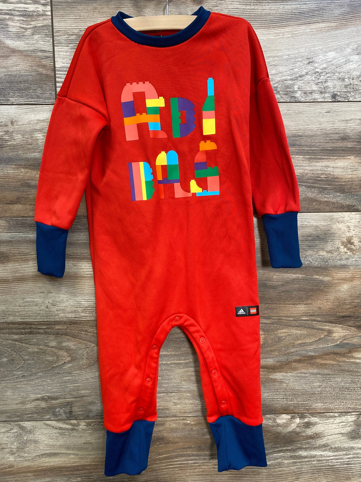 Red infant romper with navy cuffs and collar, colorful block print, Adidas and Lego logo tags