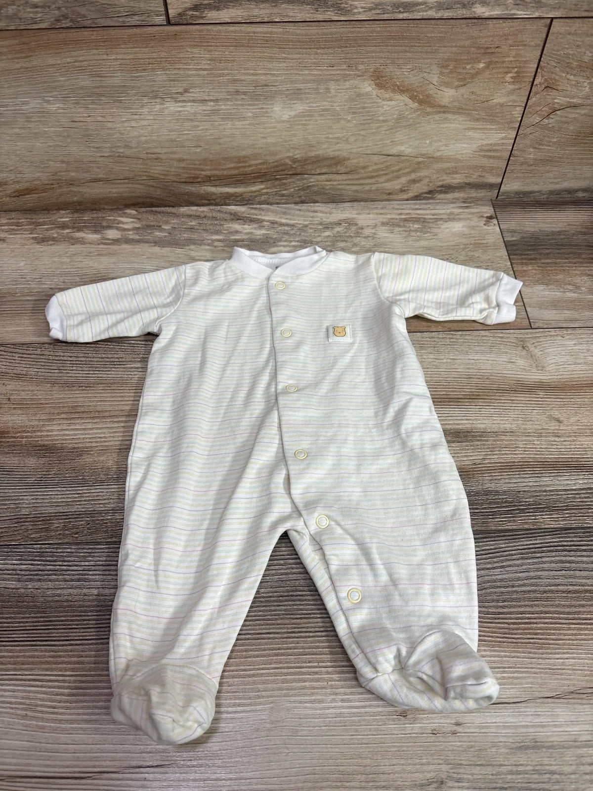 Classic Pooh by Disney yellow newborn sleeper with multicolored stripes on a wood floor