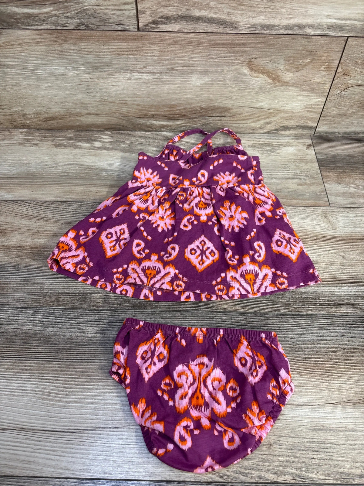Front view of Carter’s purple dress and bloomers set, size 6m, with sleeveless tiered dress and elastic bloomers on wood floor