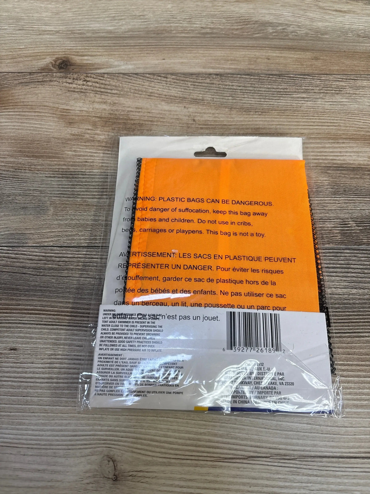 Top-down view of orange Splash 'n' Swim pool noodle chair folded and sealed in clear plastic packaging on wood surface