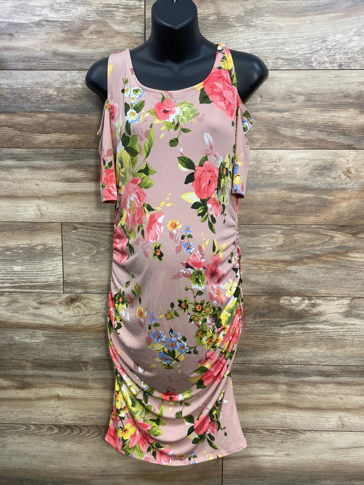 Pink floral bodycon dress with ruched sides on mannequin, wood background