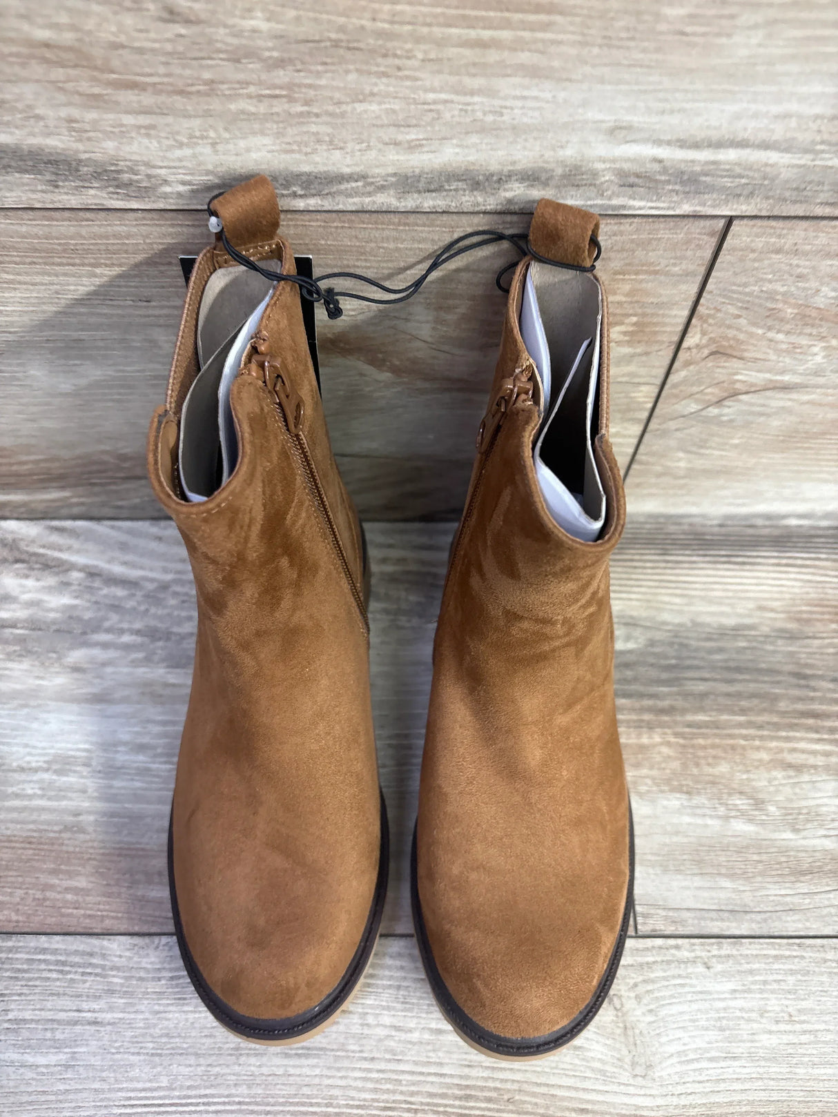 Pair of brown suede kids ankle boots on wooden floor, gently used children’s footwear