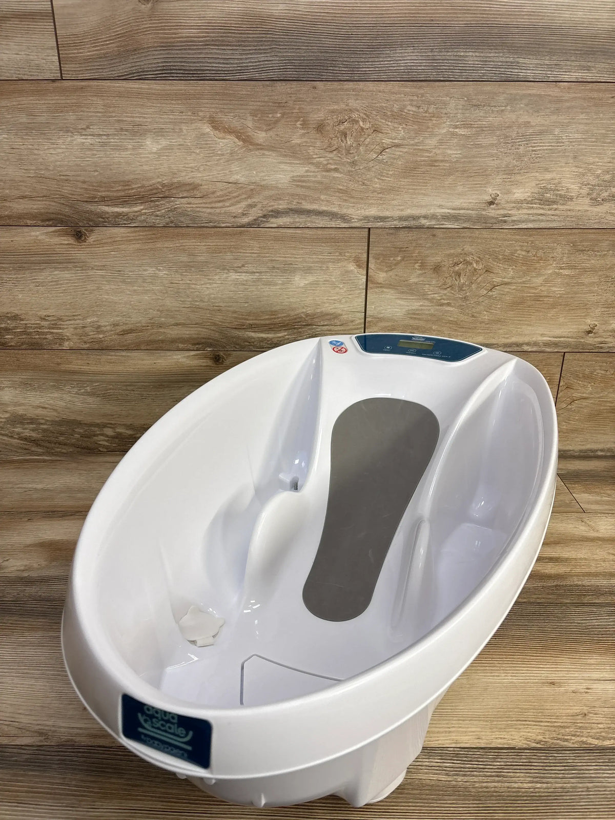 White baby bathtub with ergonomic design and digital control panel on wood floor background