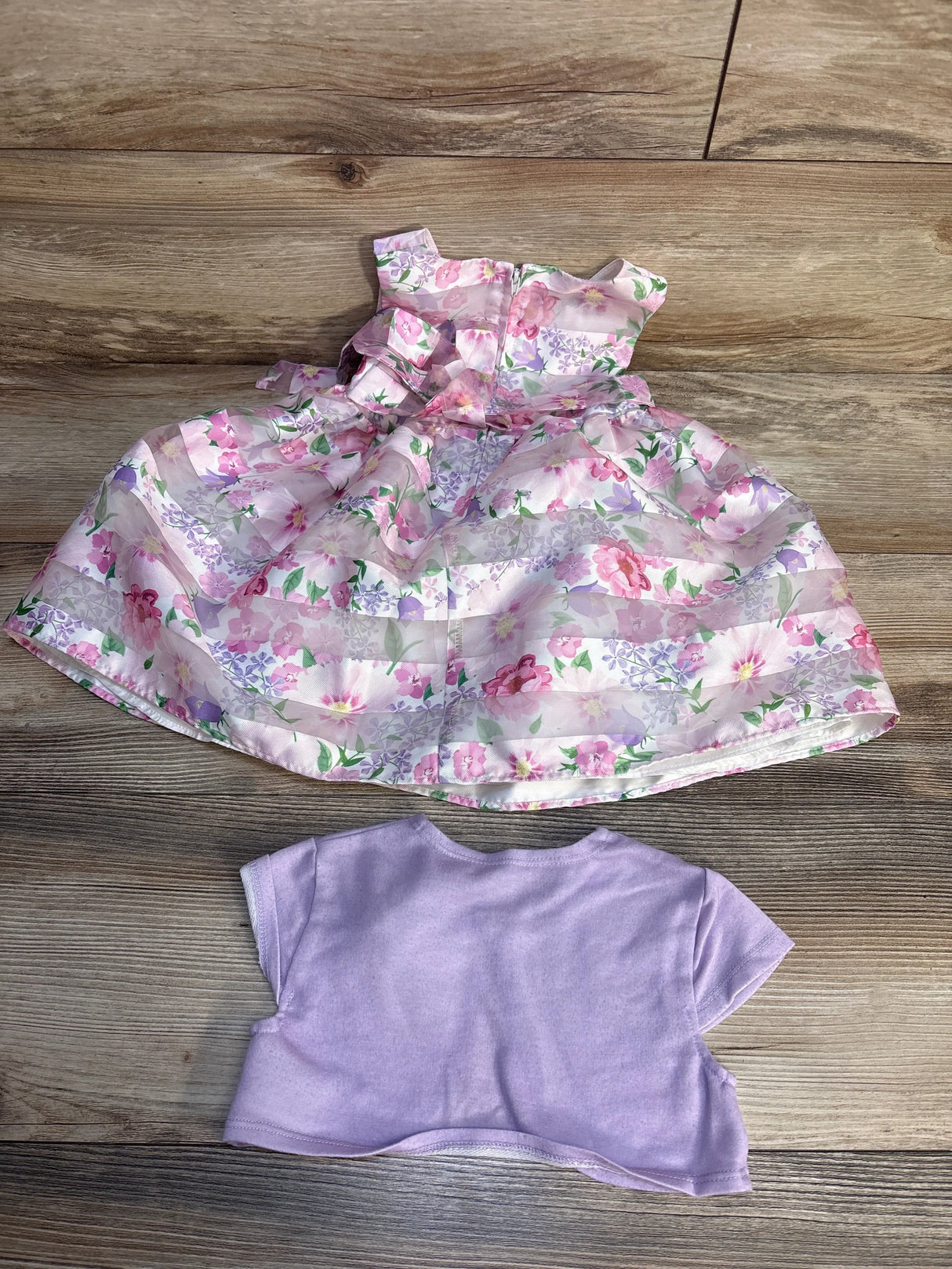 Top-down view of girls' Purple Rose 2-piece sleeveless A-line floral dress and lilac bolero cardigan, size 2T, showing full skirt on wood floor