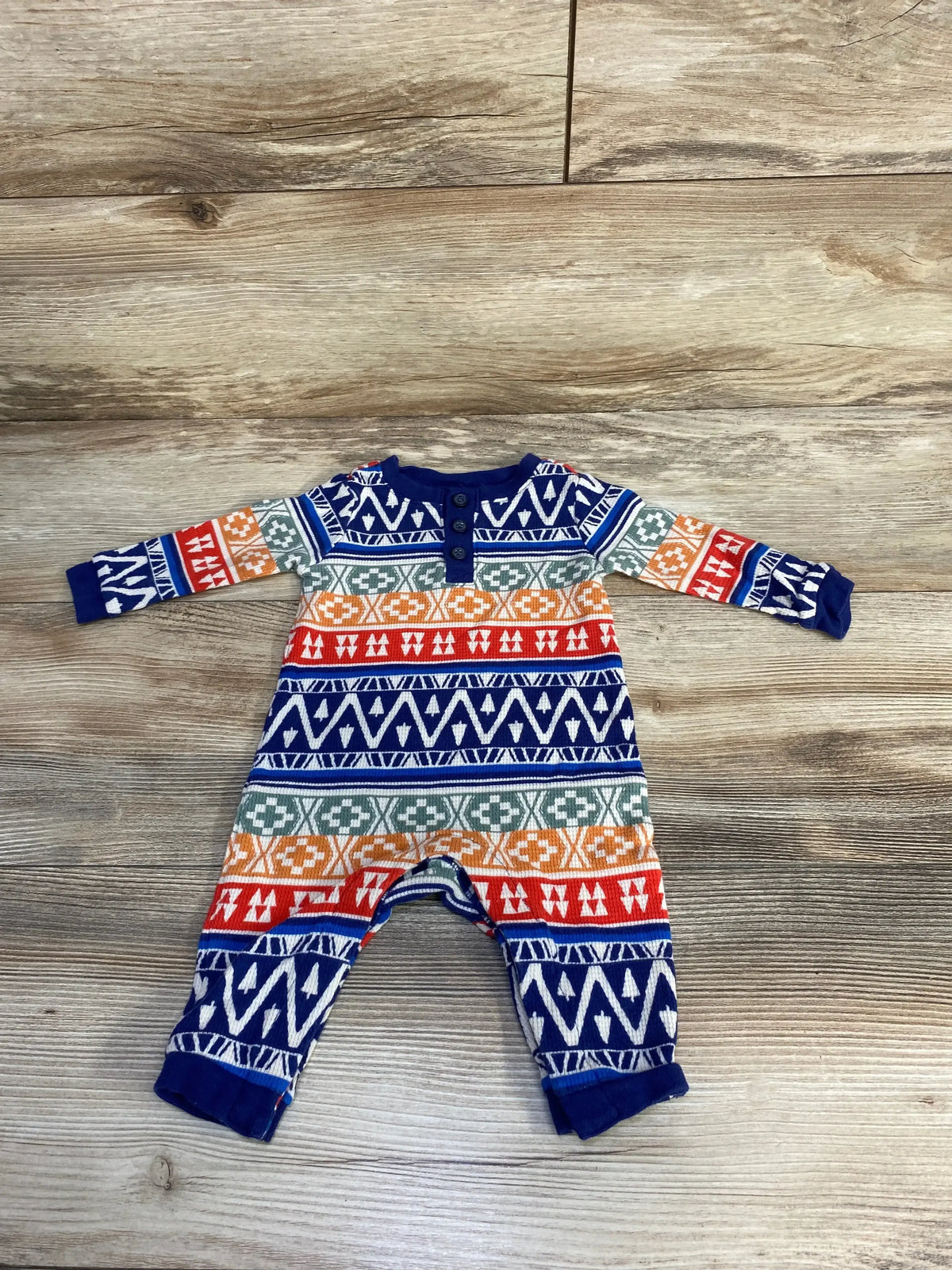 Colorful aztec patterned baby romper on wood background